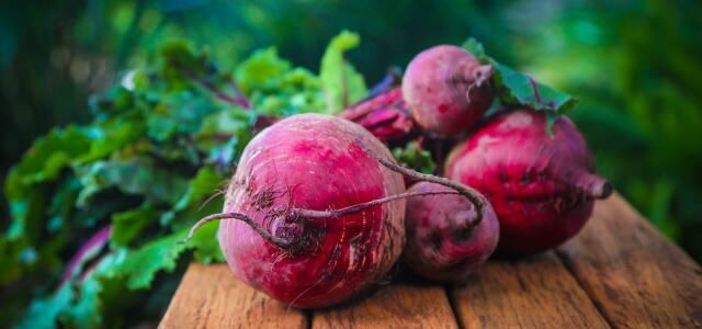Four large beetroots on a wooden surface