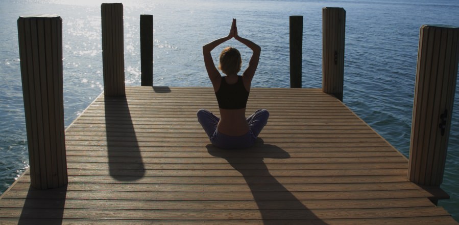 A woman meditating on a pier